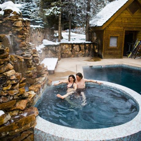 Paar sitzt im Whirlpool in der Winterhütte