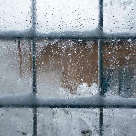 Winterfenster, Wassertropfen und Schneeflocken auf einer Fensterscheibe