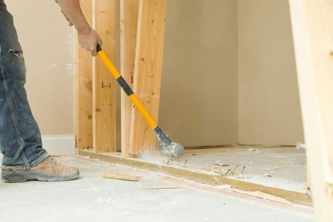 Bauarbeiter mit einem Vorschlaghammer, um Wandbolzen zu entfernen