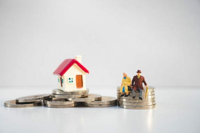 Miniaturní starší lidé sedící na hromádce mincí a mini dům jako koncept odchodu do důchodu, podnikání a pojištění