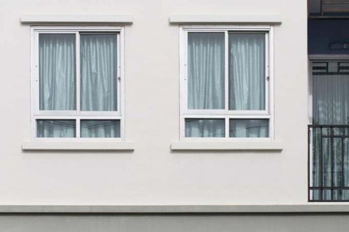 Dos ventanas modernas con cortina de protección ultravioleta en la pared blanca, vista exterior