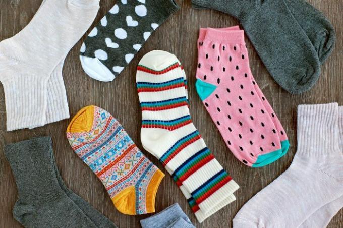 Puikaus trikotažo kojinės. Vaizdas iš viršaus. Daug kojinių mediniame fone. Įvairių spalvų ir raštų kojinės. Drabužiai šaltuoju metų laiku. Megzti drabužiai. Kojinės su ornamentu.