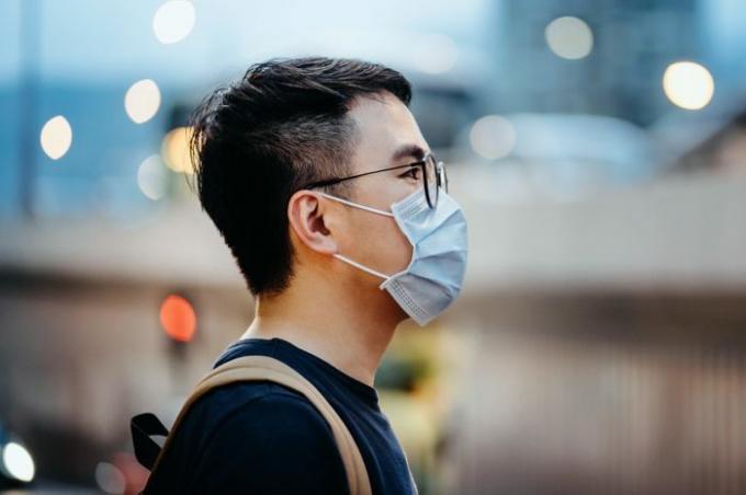 Jaunojo Azijos vyro portretas su veido kauke, apsaugančia nuo virusų plitimo mieste