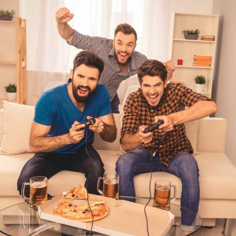 băieții care se joacă jocuri video încântați mâncând pizza și bând prieteni cu bere
