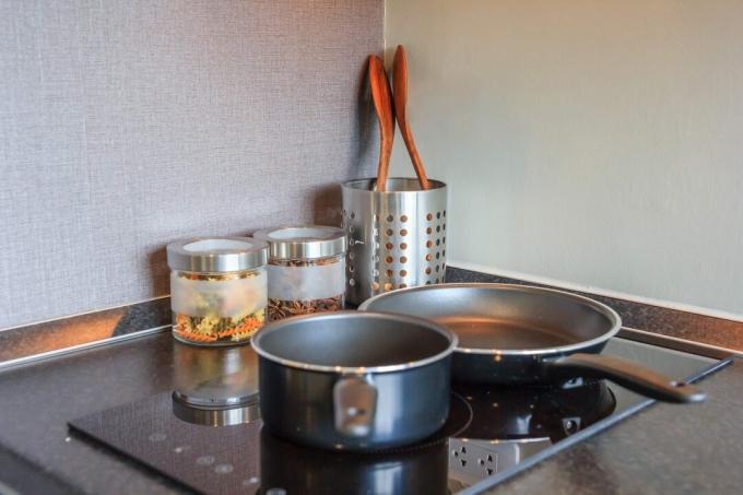 Juoda keptuvė ant viršutinės indukcinės viryklės plokštės šiuolaikinėje virtuvėje, skirta maistui gaminti, iš arti