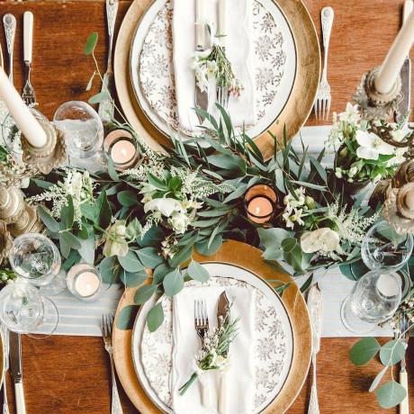 Letecký pohľad na zimný zelený veniec na hlavnom stole svadobných hostín so zlatým prestieraním a svietnikom