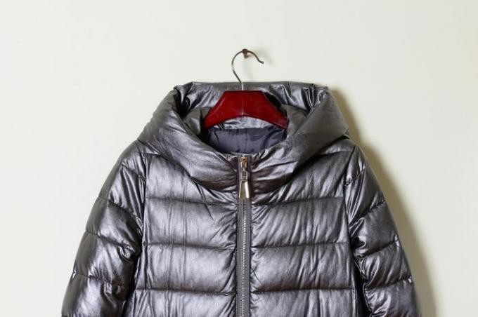 Parte de una chaqueta de invierno de mujer con capucha gris, primer plano. Ropa de calle. Colección de revestimientos de moda 2017-2018.