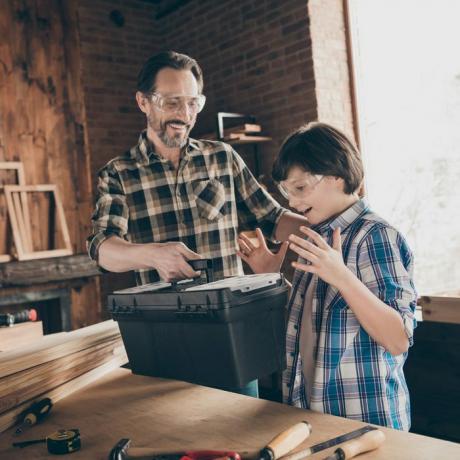 carpinteros maestro manitas papá dando un nuevo juego de herramientas a su hijo sorprendido