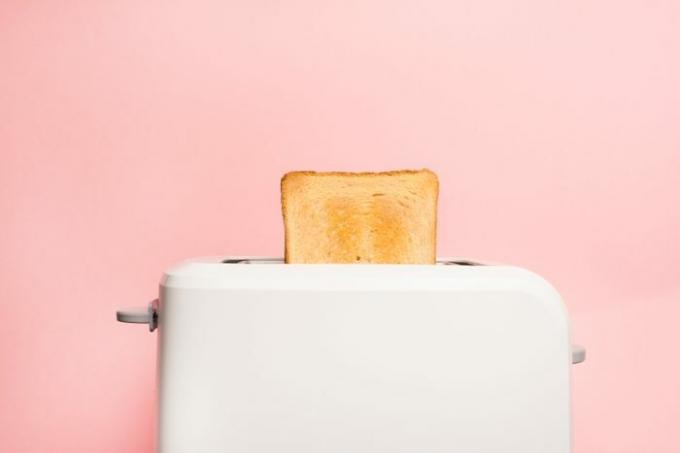 Zdrava modna hrana za zajtrk. Toast v opekaču za kruh na rožnatem ozadju.
