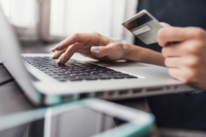Hånd holder kreditkort og bruger bærbar computer. Online shopping koncept