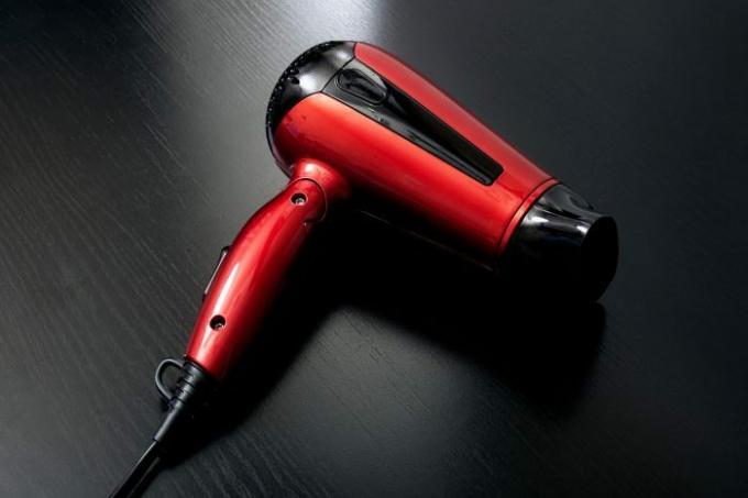 Siyah ahşap bir masa üzerinde kırmızı saç kurutma makinesi