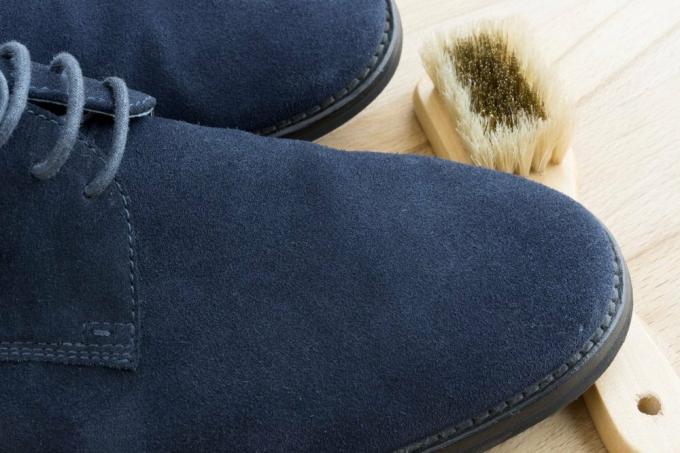 Nettoyer une paire de chaussures en daim bleu sur un bois clair