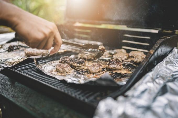 close-up op de barbecue met een tang het vlees draaien tijdens het koken