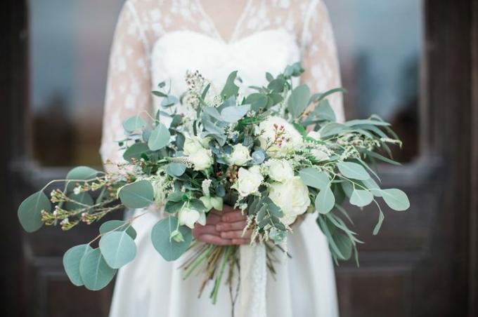 Överlämnad bröllopsbukett med rosor och eukalyptusgrönska. 