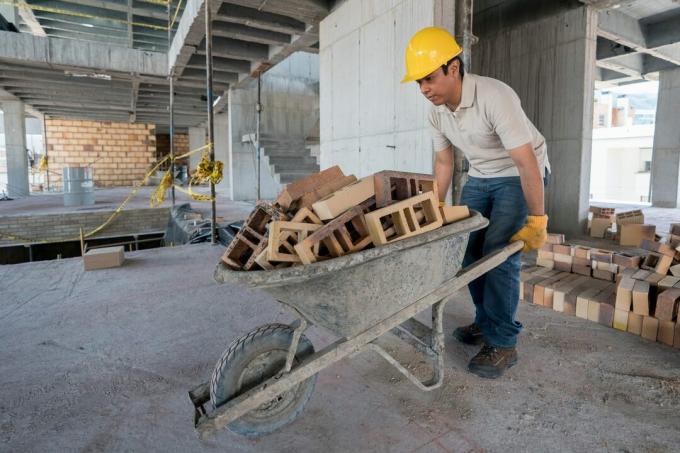 Bygningsarbejder bærer mursten på en trillebør