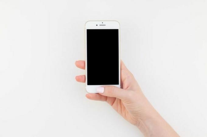 BERLIN, SAKSA - 22. KESÄKUUTA 2018: Naisen käsi pastellin manikyyrilakalla, jolla on iphone 7 eristetty valkoisella pohjalla ja kopio tilaa minimalismityylillä