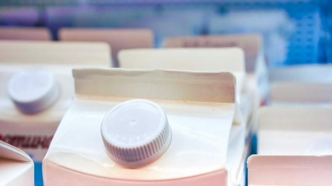 dva duga jaka reda mlijeka u bijelom kartonskom pakiranju s okruglim čepom na vrhu ostaju na bočnoj strani police u trgovini. 