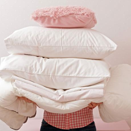 Kvinne som holder en haug med sengetøy for å sove