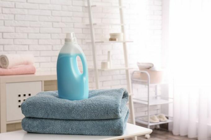 Botella de detergente y toallas limpias en la mesa en el interior, espacio para texto. Dia de lavado