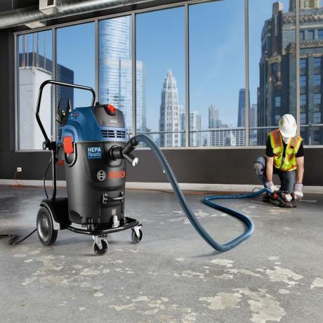 Pria menyedot debu lantai dengan penyedot debu Bosch | Kiat Pro Konstruksi