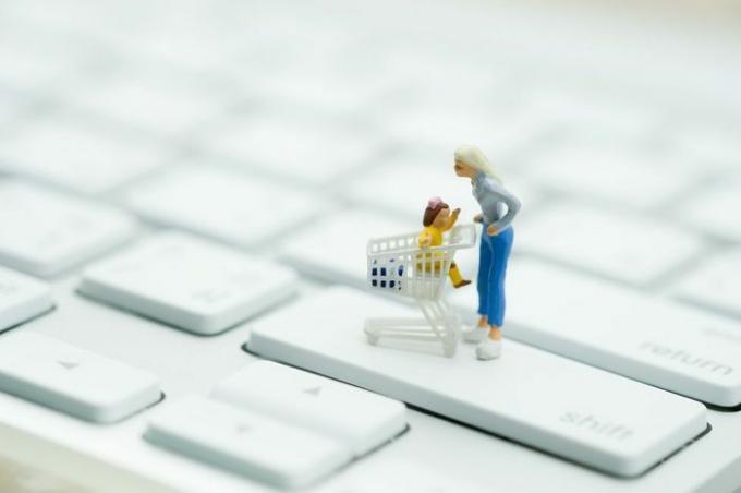 Miniatúrni ľudia: Zákazník s nákupným košíkom na klávesnici využívajúci ako základný koncept online obchodu.