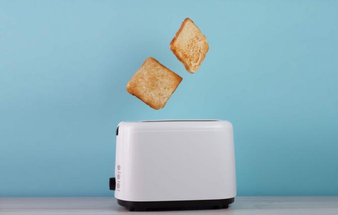Жареный тост из тостера из нержавеющей стали на синем фоне. Место для текста