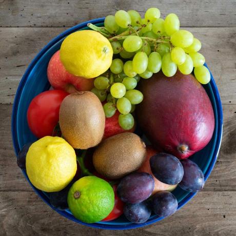 pogled na vrh posode, napolnjene s svežim sadjem, na kmečki leseni mizi