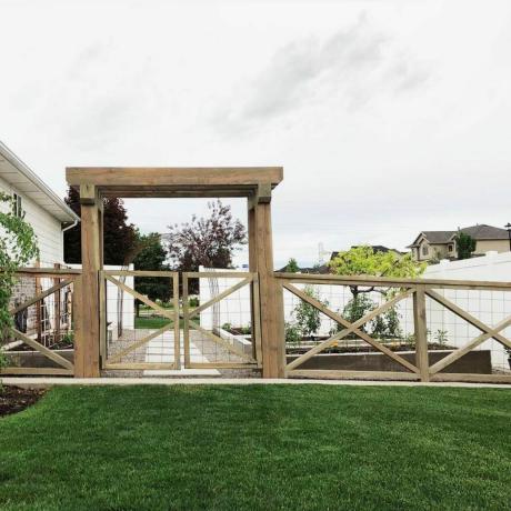 križna lesena ograja v stanovanjski soseski, ki zapira dvorišče z zeleno travo