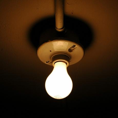 Bombilla de luz expuesta en el techo en el armario oscuro en casa