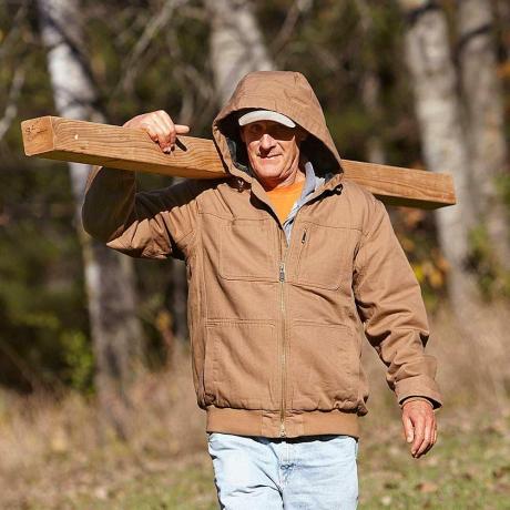 Muškarac koji nosi drvo dok nosi izdržljivu jaknu | Savjeti za graditeljstvo