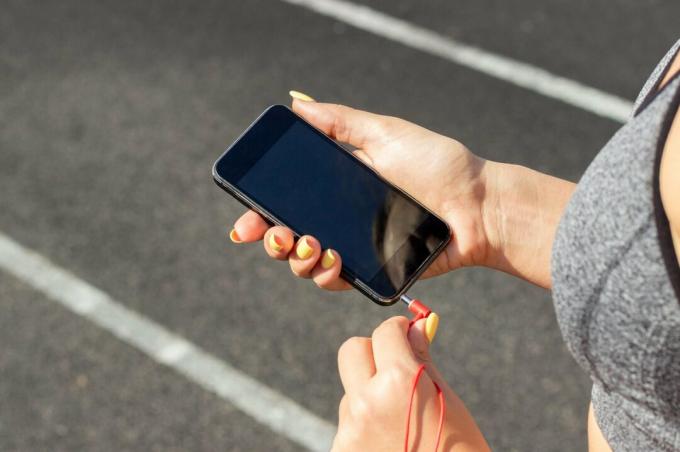 Bránička ženy, ktorá si do bežeckej dráhy nasúva slúchadlá do smartfónu
