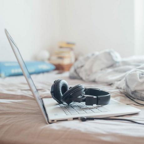 집에서 침대 위에 헤드폰과 노트북