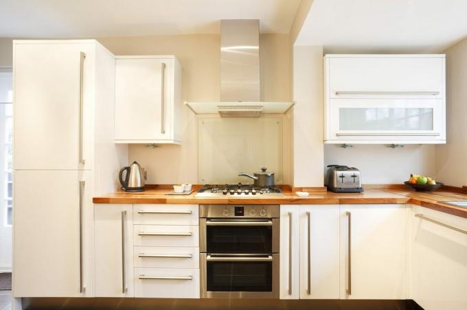 나무 조리대와 스테인리스 스틸 가전 제품 슬래브 주방 캐비닛이 있는 현대적인 흰색 주방