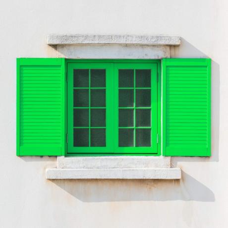 घर के बाहरी हिस्से पर रंगीन हरी खिड़की का फ्रेम