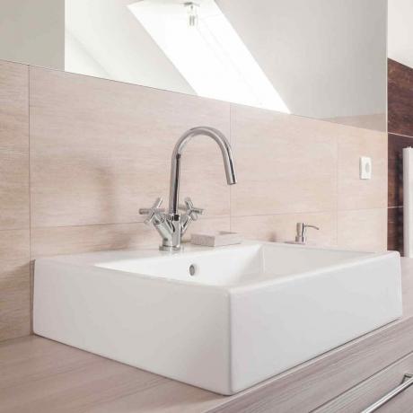 Ванная комната нейтрального цвета с квадратной керамической раковиной и блестящим хромированным смесителем