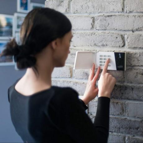 Młoda kobieta wpisując PIN bezpieczeństwa na klawiaturze alarmu domowego. System bezpieczeństwa w domu