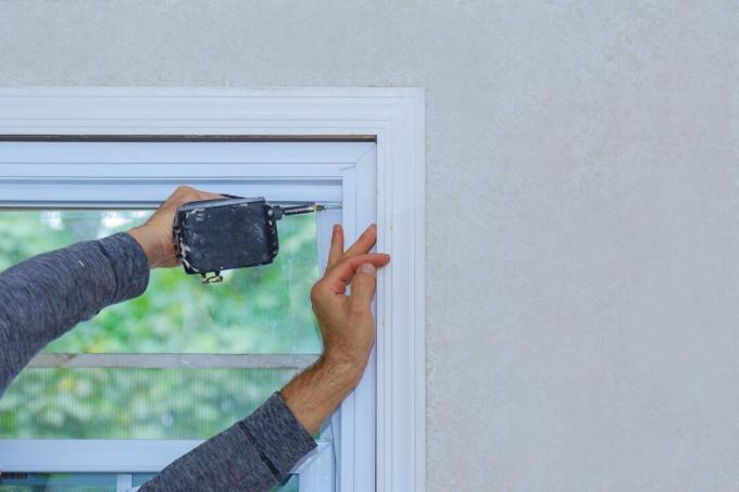 Строителен работник монтира прозорец в къщата