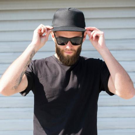 Siyah tişört ve logo alanı olan siyah bir şapka giyen hippi adam