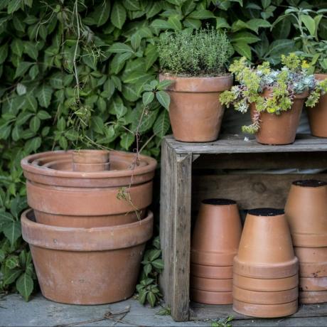 Close up de piles de pots de fleurs en terre cuite sur un sol en pierre et une boîte en bois.