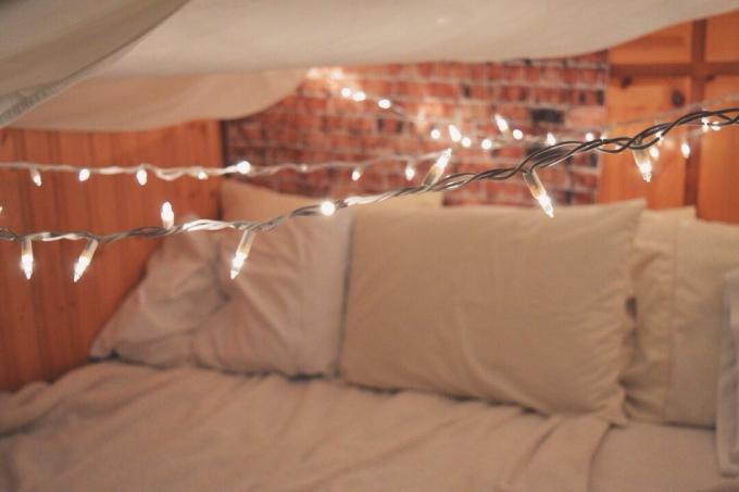 Cadena de luces iluminadas sobre la cama en casa