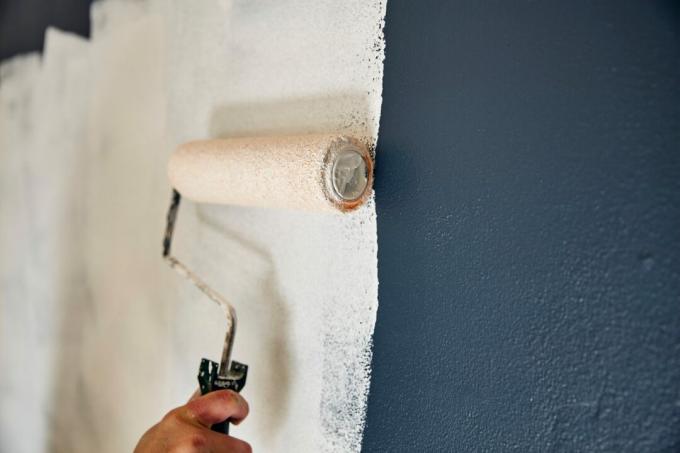 Tutup roller nyeri yang menyebarkan cat di dinding.