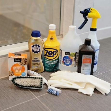 Varios productos y herramientas de limpieza de baldosas y lechada en el piso del baño