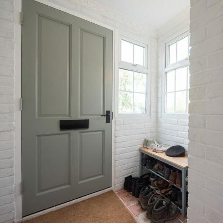 Az előszoba tornácának általános belső képe zsálya zöld bejárati ajtóval és cipőtartó tárolóval az otthonon belül