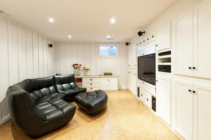 मनोरंजन केंद्र, सोफे और फ्लैट स्क्रीन टेलीविजन के साथ आवासीय घर का तैयार बेसमेंट।