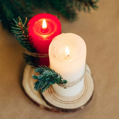 საშობაო სადღესასწაულო ზამთრის მისალოცი ბარათი. წითელი სანთელი, ფიჭვის ტოტები, ხის ნატურალური უჯრა. სახლის ინტერიერის გაფორმება.