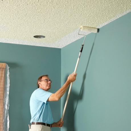 Čovjek kotrlja tamniju boju na teksturirani strop | Savjeti za graditeljstvo