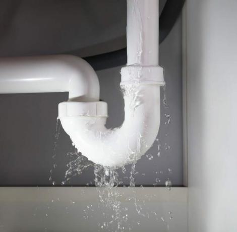 Nærbilde av vann lekker fra den hvite vaskerøret