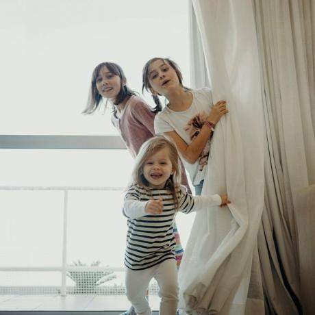 Три младе девојке вире иза завесе