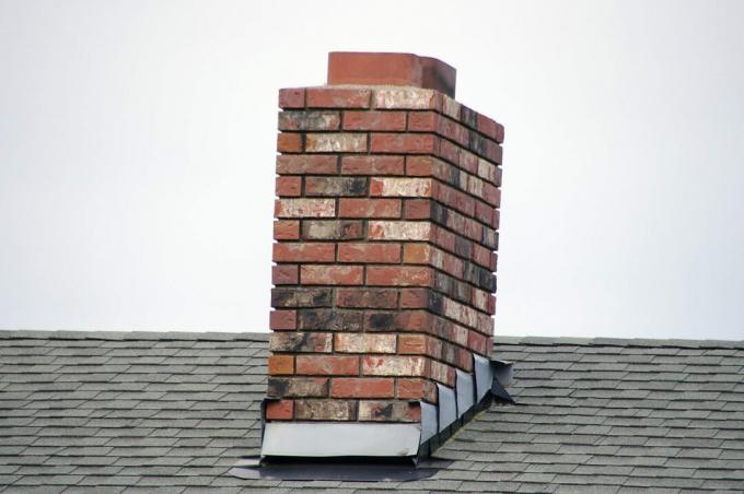 Een bakstenen kleine schoorsteen op het dak van huis