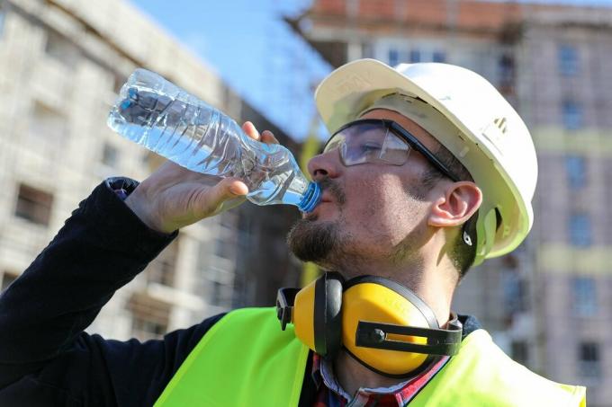 Chef auf der Baustelle mit einer Flasche Wasser